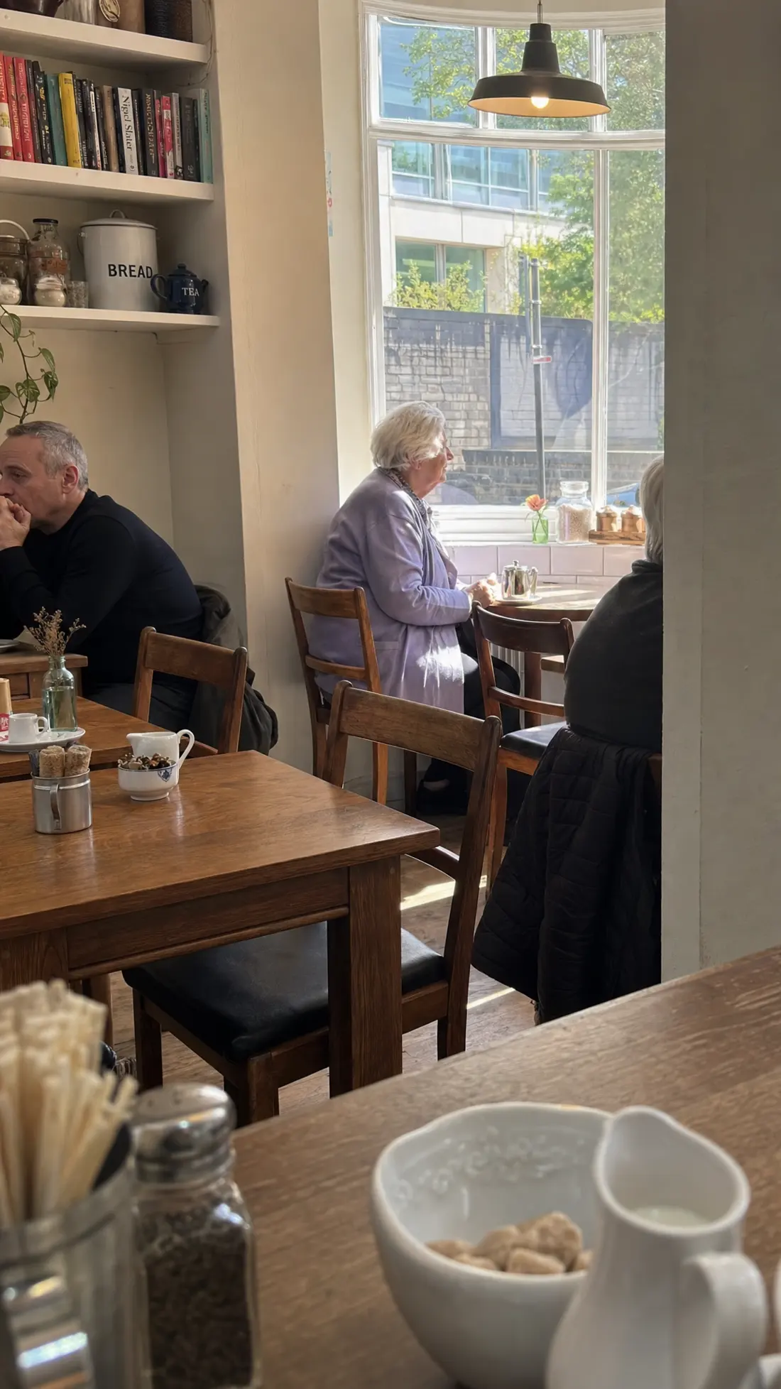 Inside the café: wooden tables, a big sash window and regulars over tea