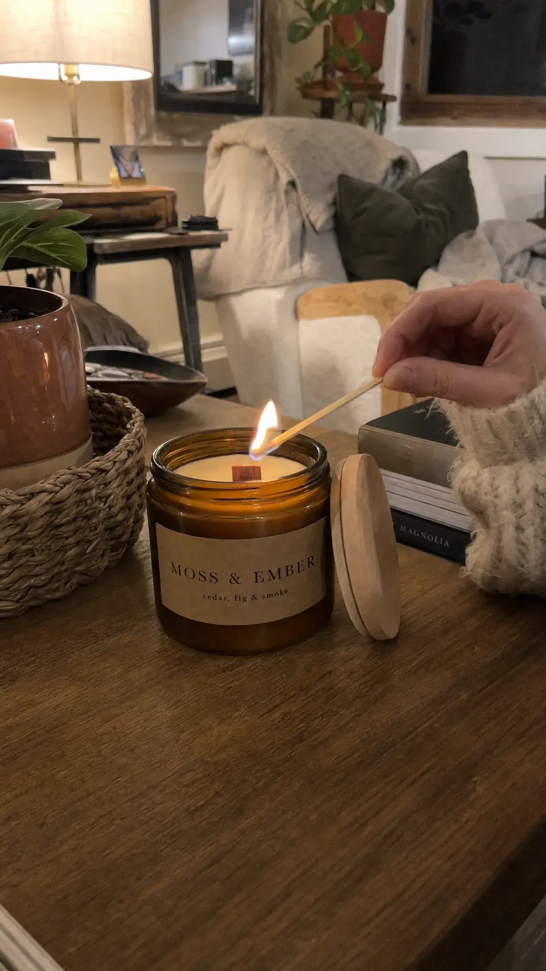 A match lighting the wooden wick of a Moss & Ember candle